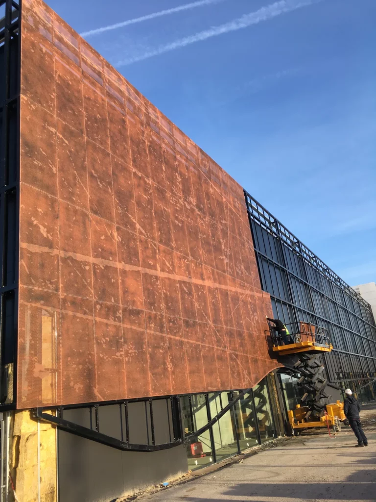 Perforated façade of the ice rink, random pattern forming a fresco